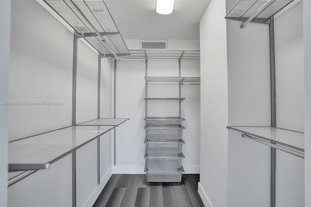 walk in closet with dark wood-type flooring