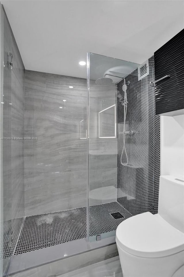 bathroom featuring a tile shower and toilet