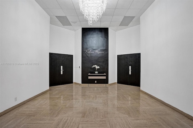 empty room with a paneled ceiling and an inviting chandelier