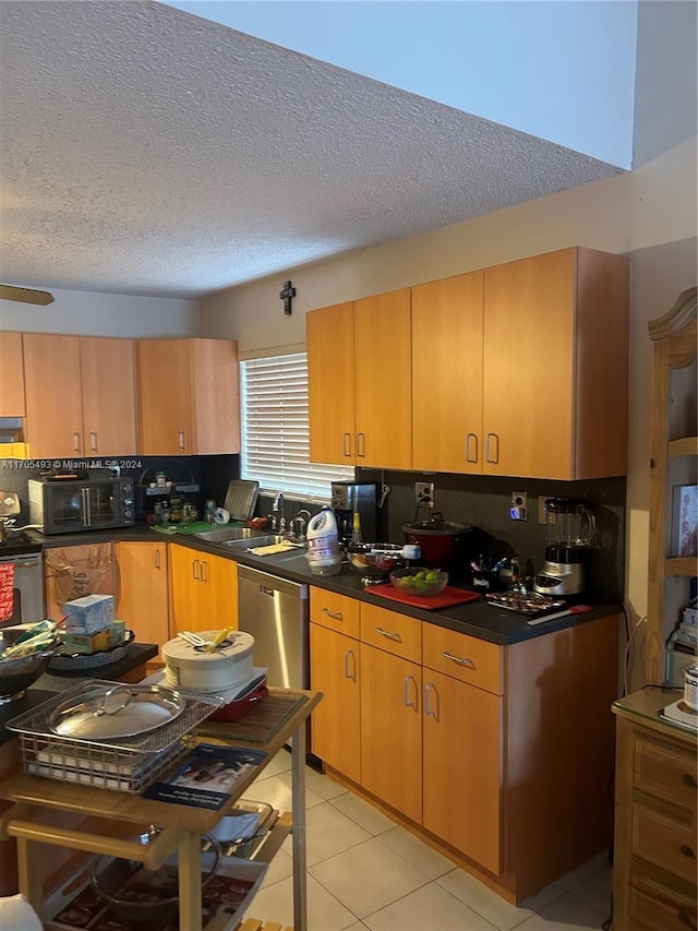 kitchen featuring sink, decorative backsplash, a textured ceiling, light tile patterned flooring, and stainless steel appliances