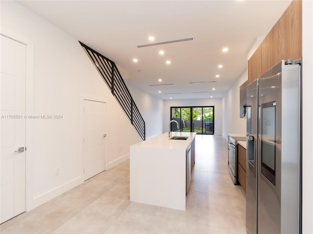 kitchen with appliances with stainless steel finishes, a center island with sink, and sink