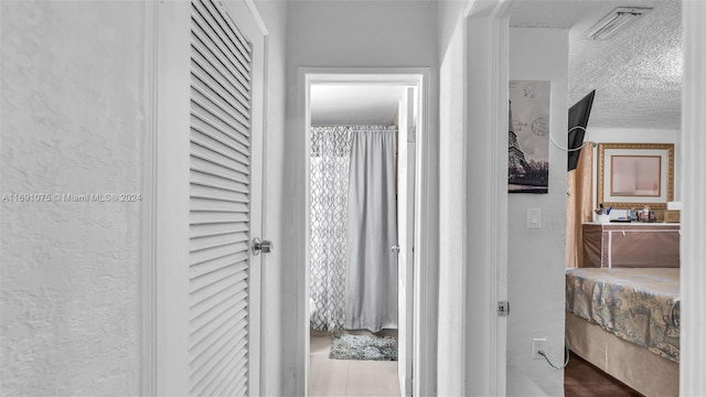 corridor featuring tile patterned floors and a textured ceiling