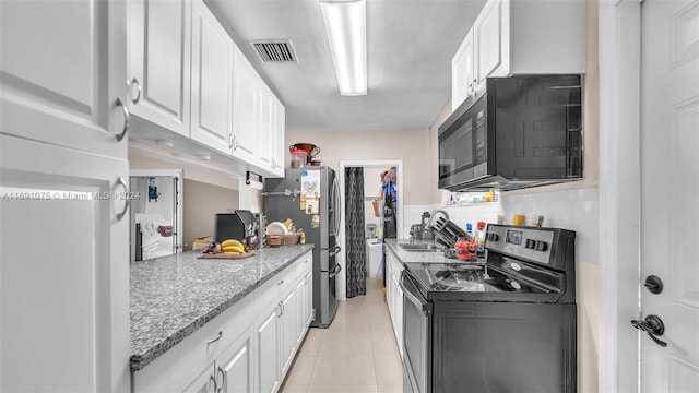 kitchen featuring light stone countertops, white cabinetry, sink, stainless steel appliances, and light tile patterned floors