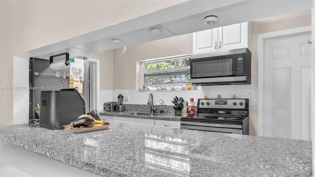 kitchen with white cabinets, sink, decorative backsplash, appliances with stainless steel finishes, and light stone counters