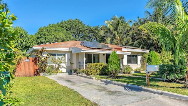 ranch-style home with a front yard and solar panels