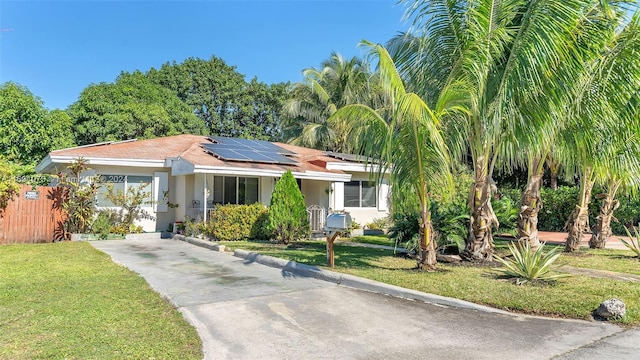 view of front of home with a front yard and solar panels