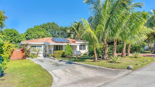 view of front of home featuring solar panels and a front lawn