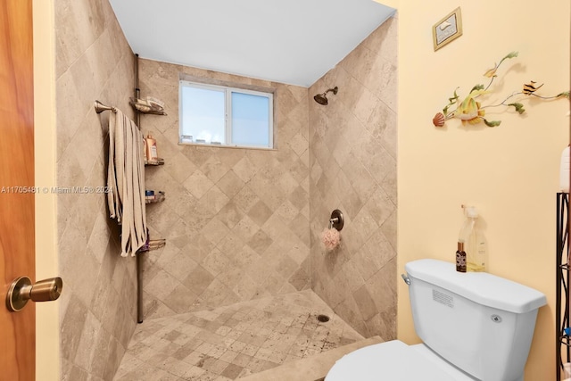 bathroom with a tile shower and toilet