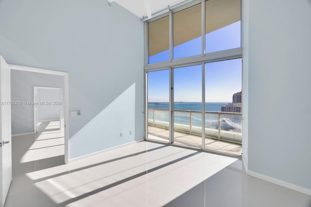 tiled spare room featuring a water view