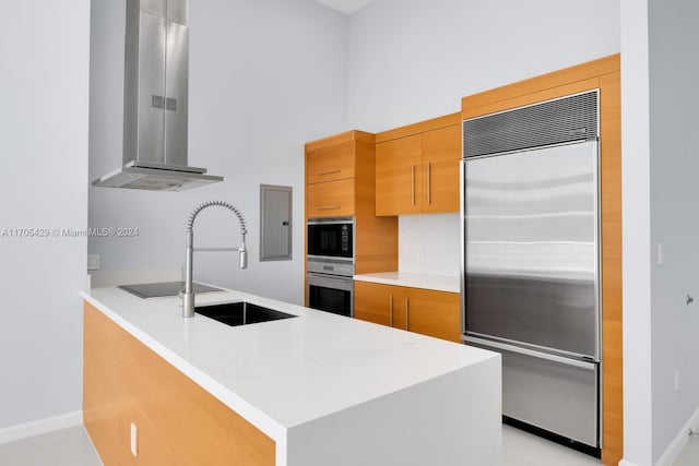 kitchen with kitchen peninsula, light stone countertops, sink, black appliances, and range hood