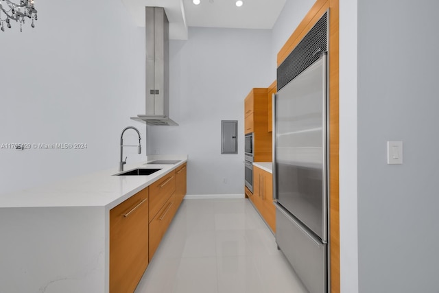 kitchen with stainless steel built in refrigerator, light stone countertops, wall chimney exhaust hood, and sink