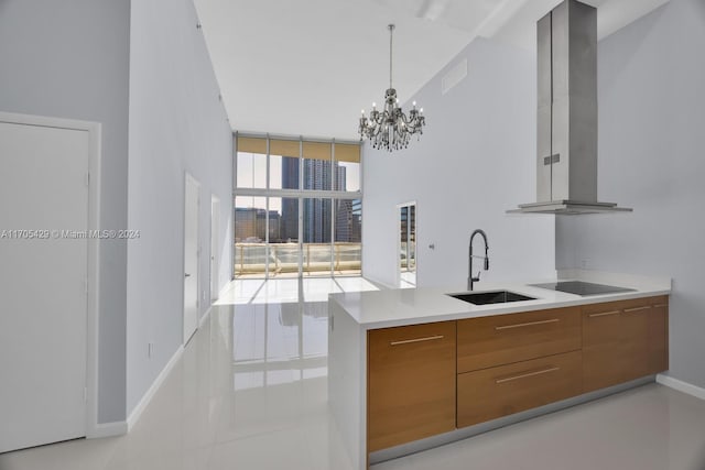 kitchen with sink, wall chimney exhaust hood, black electric cooktop, light tile patterned floors, and a notable chandelier