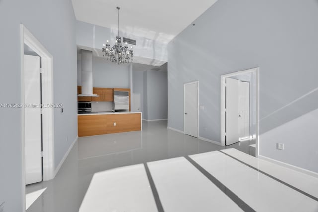 interior space with decorative light fixtures, an inviting chandelier, black microwave, and wall chimney range hood