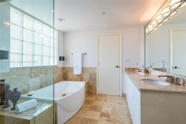 bathroom with tiled bath, vanity, and tile walls