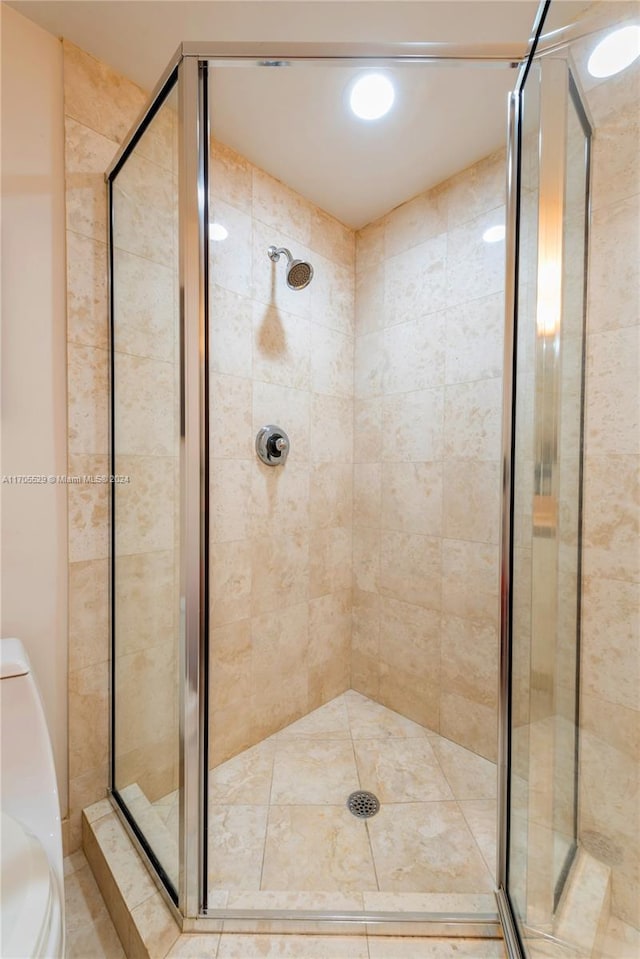 bathroom featuring toilet and a shower with door