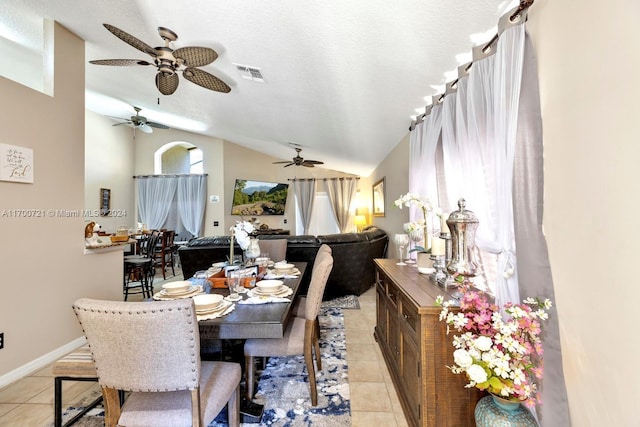 tiled dining area featuring ceiling fan, lofted ceiling, and a textured ceiling