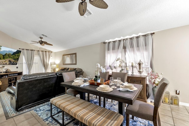 tiled dining space featuring ceiling fan, a textured ceiling, and vaulted ceiling