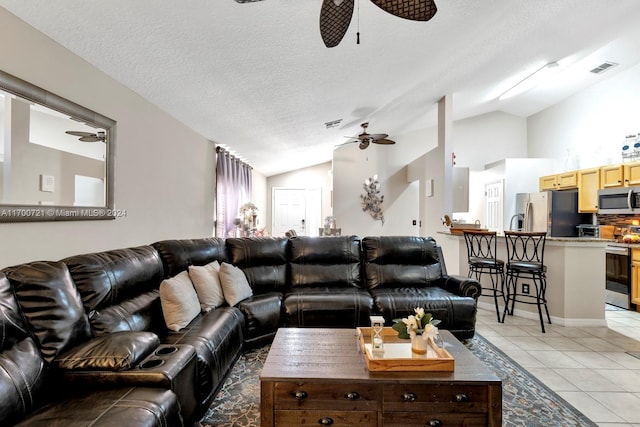 living room featuring a textured ceiling, vaulted ceiling, and light tile patterned flooring