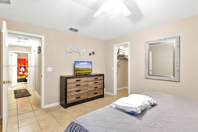 tiled bedroom featuring ceiling fan, a spacious closet, a textured ceiling, and a closet