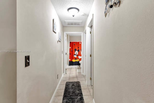 corridor with light tile patterned floors and a textured ceiling