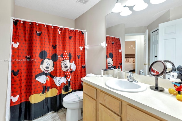 bathroom with tile patterned flooring, vanity, a textured ceiling, and toilet