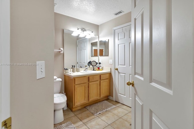 bathroom featuring tile patterned floors, vanity, a textured ceiling, and toilet