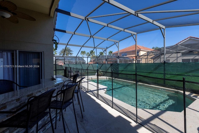 view of swimming pool with glass enclosure, ceiling fan, and a patio area