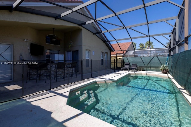 view of pool featuring a bar, glass enclosure, and a patio area