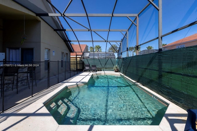 view of pool with glass enclosure and a patio