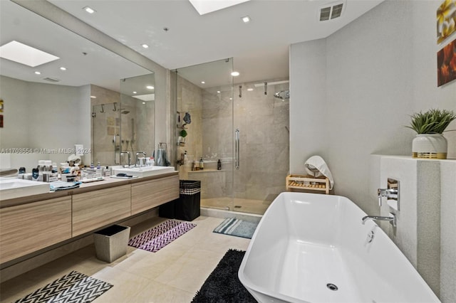 bathroom featuring tile patterned flooring, vanity, shower with separate bathtub, and a skylight