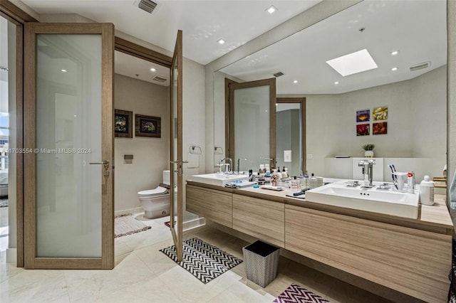 bathroom featuring vanity, toilet, a shower with shower door, and a skylight