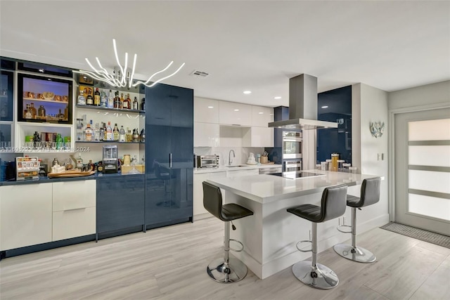 kitchen featuring a kitchen breakfast bar, a kitchen island, light hardwood / wood-style floors, white cabinetry, and island exhaust hood