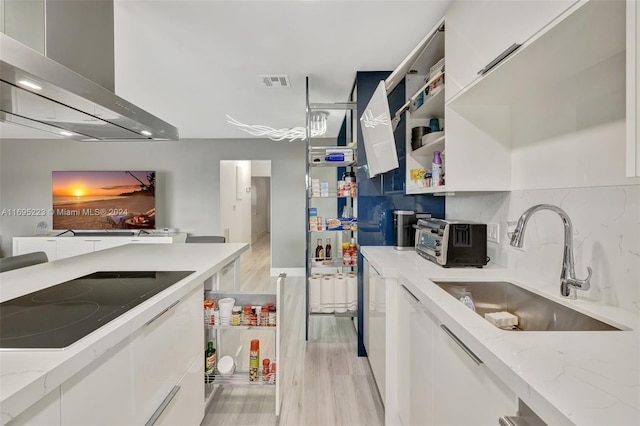 kitchen with white cabinets, wall chimney exhaust hood, and light hardwood / wood-style floors