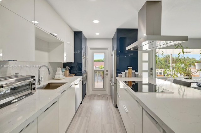 kitchen with island range hood, white cabinets, and light stone counters