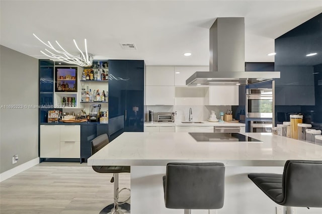 kitchen with black electric stovetop, sink, light hardwood / wood-style floors, white cabinetry, and island exhaust hood