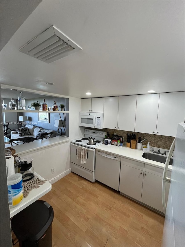 kitchen featuring white cabinetry, sink, backsplash, light hardwood / wood-style floors, and white appliances