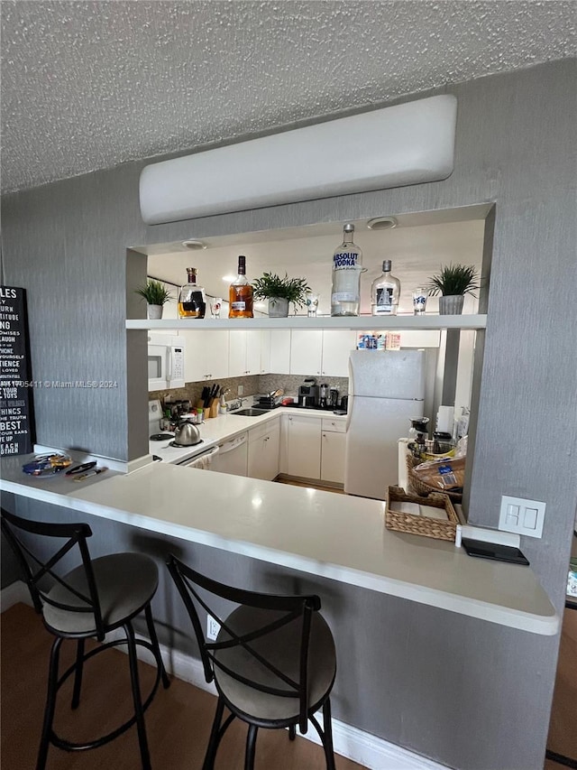 13499 Biscayne Blvd Unit 1601, North Miami, FL 33181 - kitchen with white appliances, a peninsula, white cabinets, a breakfast bar area, and open shelves