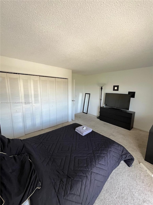 bedroom with light colored carpet, a textured ceiling, and a closet