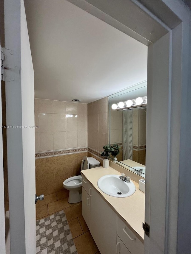 bathroom featuring tile patterned flooring, vanity, toilet, and tile walls