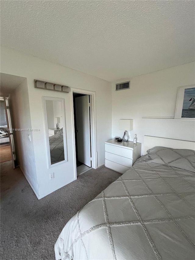 bedroom featuring dark colored carpet and a textured ceiling