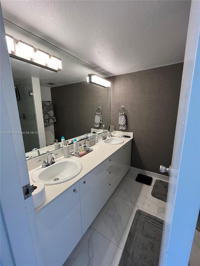 bathroom featuring a shower with door, vanity, a textured ceiling, and toilet