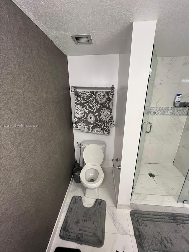 bathroom featuring a textured ceiling, an enclosed shower, and toilet