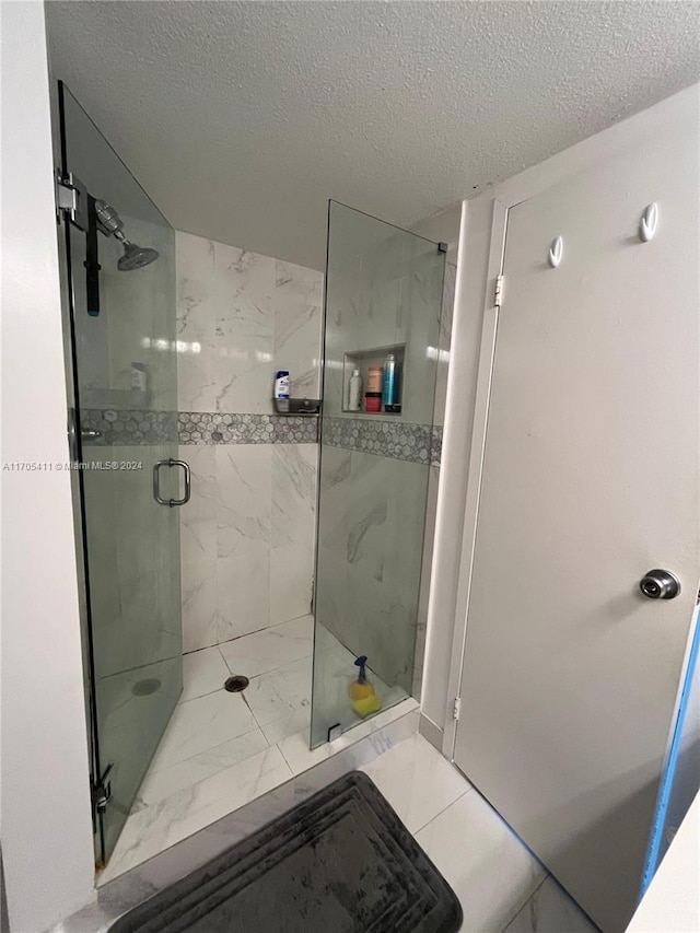 bathroom with a textured ceiling and a shower with shower door