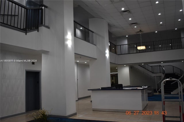 kitchen with a drop ceiling, elevator, light tile patterned floors, and a high ceiling