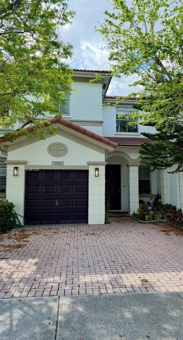 view of front of house featuring a garage, decorative driveway, and a tiled roof