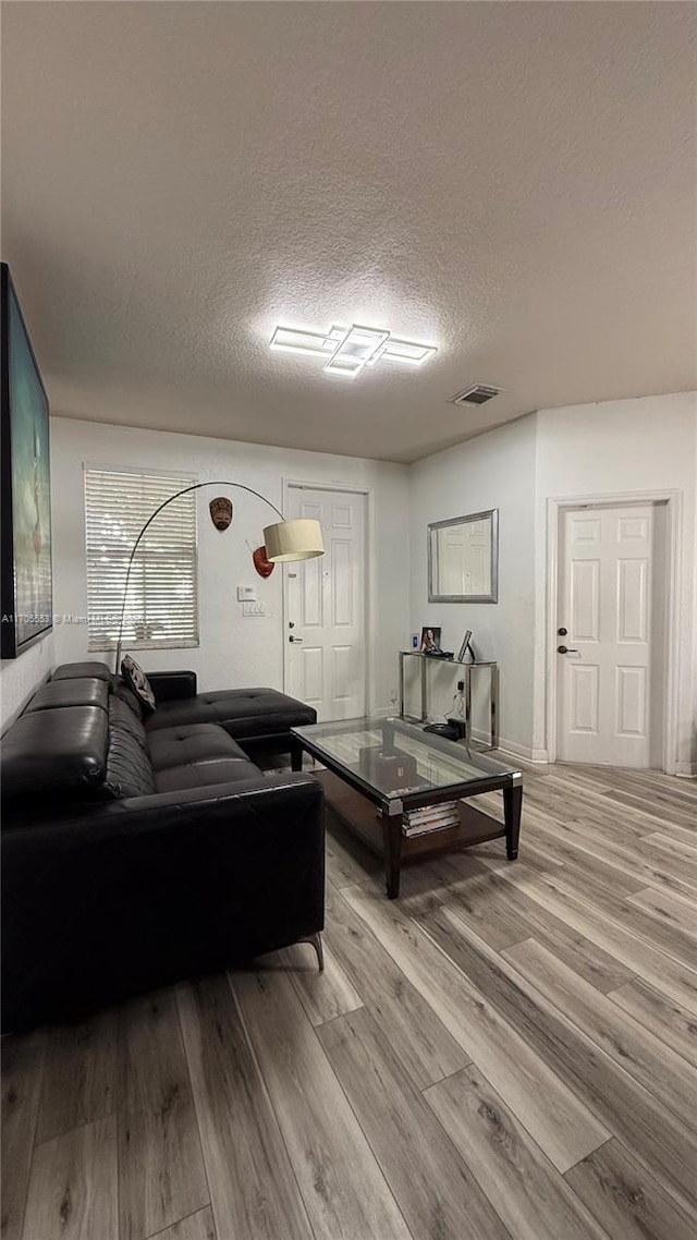 living room with visible vents, a textured ceiling, and wood finished floors