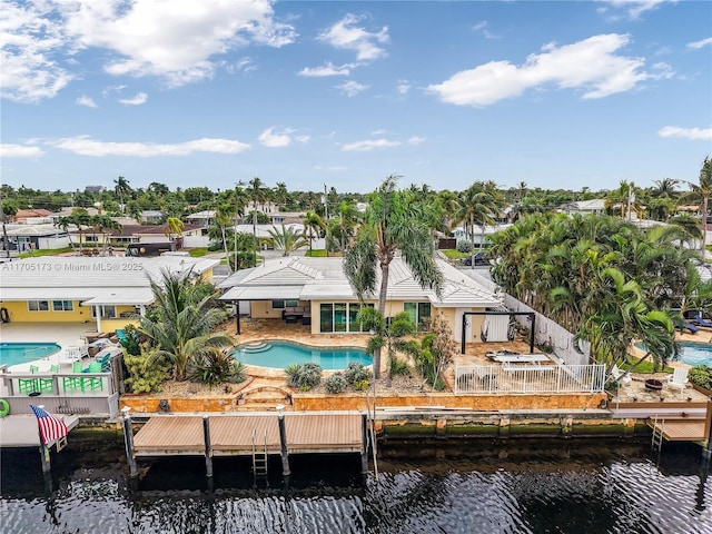 rear view of house featuring fence, a water view, a residential view, an outdoor pool, and a patio