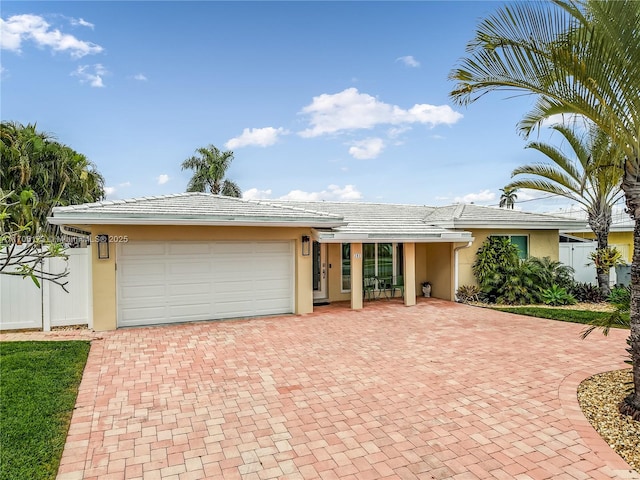 ranch-style house with decorative driveway, fence, and stucco siding