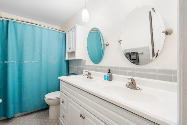 bathroom with toilet, vanity, and tasteful backsplash