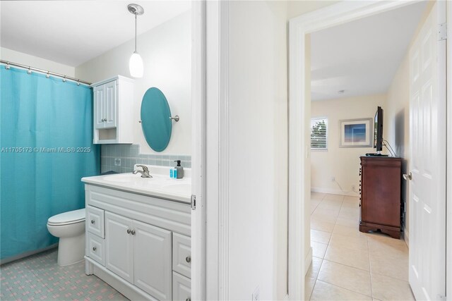 bathroom featuring toilet, vanity, backsplash, and tile patterned floors